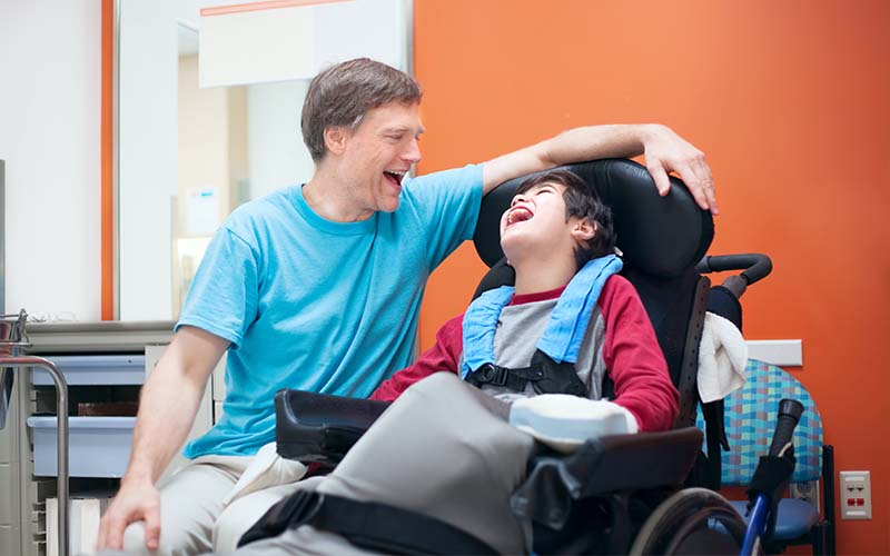 Father laughing with son in wheelchair